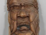 une vieille sculpture en bois représentant le visage d'un homme, posée sur une table