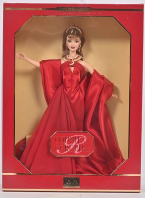 La poupée Barbie se trouve dans une boîte rouge et porte une robe rouge.