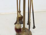 three brooms and a broom brush on a stand