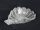 a glass shell shaped object on a black surface