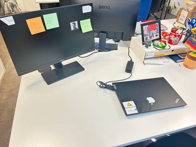 un bureau sur lequel sont posés deux écrans et un ordinateur portable