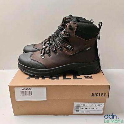 un gros plan sur une paire de chaussures de randonnée marron posées sur une boîte