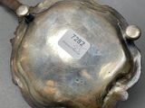 a silver plate with a metal handle on a table