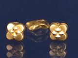 une paire de boucles d'oreilles en or sur un fond bleu avec des reflets