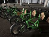 several green bikes are lined up in a row in a warehouse