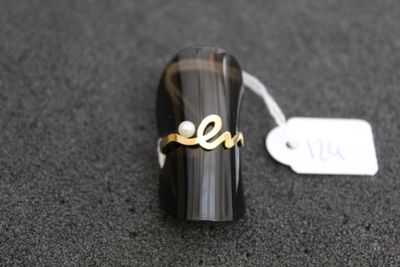 une bague sur laquelle est gravé un nom, posée sur une table