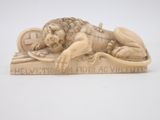 sculpture of a lion laying on top of a wooden plaque