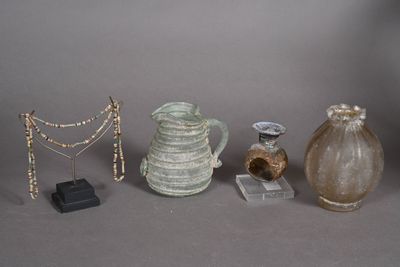 trois vases, un collier et d'autres objets exposés sur une table