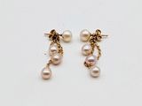 two pearl earrings with gold chains on a white surface
