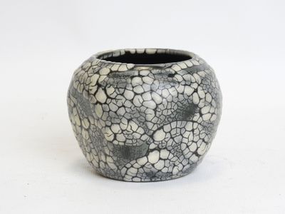 a black and white vase sitting on a white surface