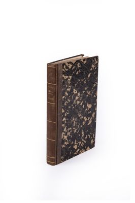an old book sitting on top of a white table next to a white wall