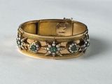 a close up of a gold bracelet on a white surface