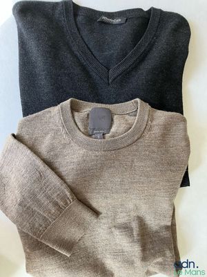 deux pulls pour homme posés l'un à côté de l'autre sur une surface blanche