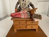 a figurine of an old woman sitting on a bed