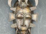 an image of a metal mask hanging on the wall of a room