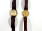 two watches sitting side by side on a white surface