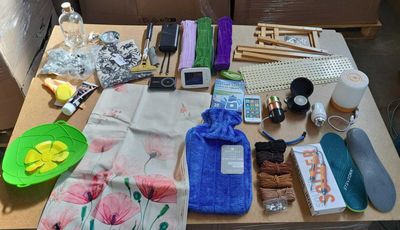 une table sur laquelle se trouvent de nombreux objets, notamment un téléphone portable, une serviette, une bouteille d'eau, une coque de téléphone portable et d'autres objets