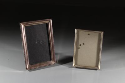 une paire de cadres photo anciens en argent posés sur une surface blanche