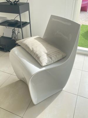 une chaise blanche avec un coussin dessus, dans un salon
