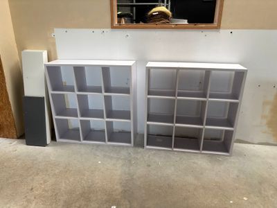 two bookshelves in the corner of a room with a mirror on the wall