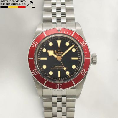 a red and black watch on a silver bracelet