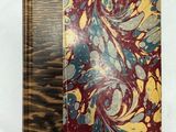 un vieux livre à la couverture en bois posé sur une table blanche