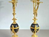 two gold and black vases sitting on top of each other