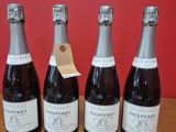 quatre bouteilles de vin sont alignées sur une table en bois