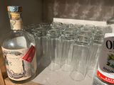many glasses and a bottle of alcohol sitting on a counter
