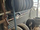 many tires stacked up on the side of a truck