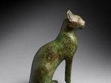 an egyptian bronze statue of a cat sitting on its hind legs