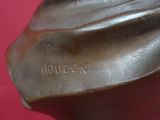 un gros plan d'une statue en bronze posée sur un fond rose