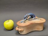 a small box with a figurine on it next to an apple
