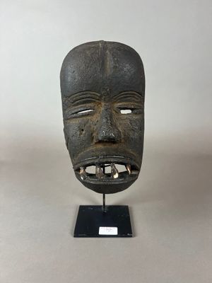 un gros plan d'un masque en bois posé sur un socle, lui-même posé sur une table