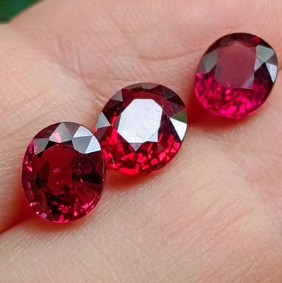 deux pierres précieuses de couleur rubis posées sur le doigt d'une personne