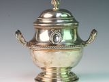 a silver vase with a lid on a white table