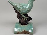 green bird on a branch figurine on a white background