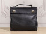 black leather briefcase sitting on top of a wooden table next to a wall