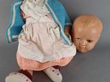 a doll that is sitting next to a doll on the floor
