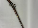 Un vieux pistolet et un fusil sont exposés dans une vitrine