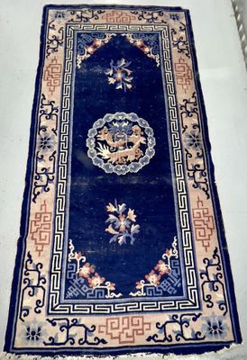 un tapis posé à même le sol, bordé d'une frange bleue