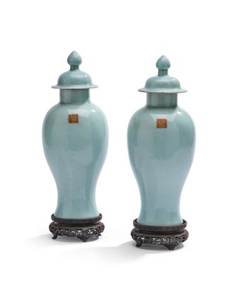 une paire de vases bleus avec couvercles, posés sur des socles, sur une surface blanche
