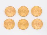 six pièces d'or sont disposées en ligne sur une surface blanche