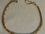gros plan d'un bracelet en or sur une surface blanche