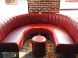 une banquette en cuir rouge avec un pouf rouge devant un mur de briques