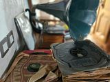 an old record player sitting on top of a table next to a stack of old records