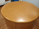 a round wooden table with drawers on it in a room