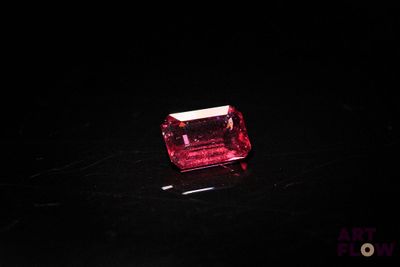 un diamant rose sur une surface noire dans l'obscurité