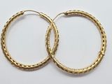 two pairs of gold hoop earrings on a white surface