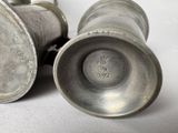 two silver vases sitting next to each other on a table